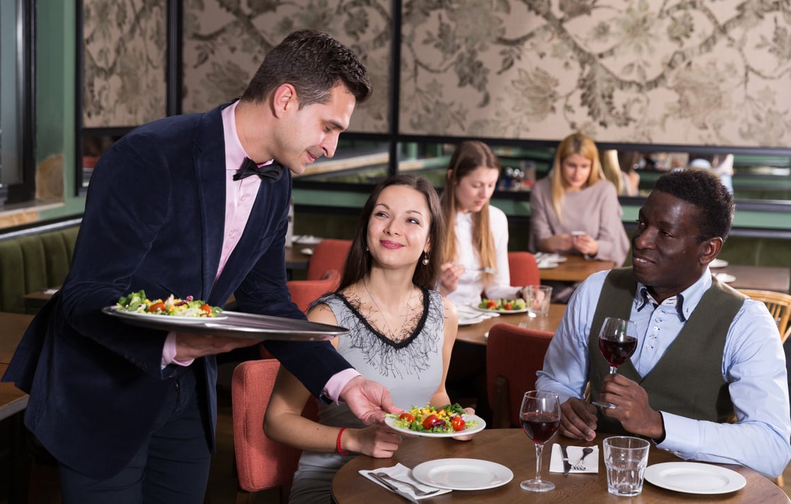 Waiter serving couple in restaurant